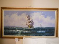 Full view of framed acrylic sea scape painting showing sailing ship on ocean under cloudy sky.