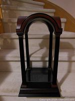 Full view of the cherry wood and black accented display stand showing the arch top and fluted columns.