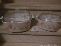 Both Corningware casserole dishes with lids, showing flower pattern and size difference.