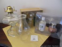 Full lot of oil lamps and boxed oil lamp sets on yellow cloth, showing all components in one view.