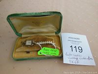 Front view of vintage Birks 10K GF ladies watch in green velvet box on beige surface, with auction lot number tag.