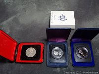 Three uncirculated RCM silver dollars from 1970, 1975, and 1976 in presentation cases.