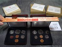 Four Royal Canadian Mint uncirculated coin sets displayed with a ruler for scale. Coins include multiple denominations in black velvet-lined leather cases with official documentation and cardboard boxes in the background.