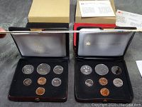 Four open coin sets in cases showing Canadian coins and velvet interior linings. Two black and red cases, coins visible; official letters seen in background.