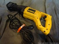 Yellow DeWalt reciprocating saw with attached power cord shown on grey fabric.