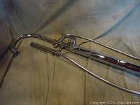 Chrome finished free standing bath filler with curved spout, handheld shower, and lever control lying flat on fabric backdrop.