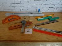 Overview of all table saw accessories and accessories spread on wooden surface against white brick wall