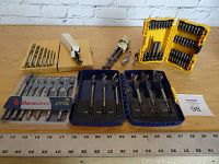 Full view of all drill bit sets, cases and loose bits spread out on a wooden table