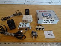 Wide view of lot contents on wooden surface: Lexx antenna signal finder in box, signal amplifier, power adapters, and cable splitters.