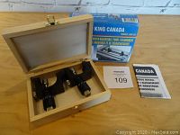 Micro-adjustable knife jig components in wooden box with product box and manual on table.