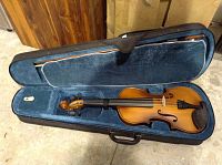 Open violin case showing Mendini violin inside, with blue soft interior lining and black chin rest, fingerboard, tailpiece.