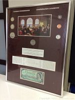 Frontal view of framed display showing burgundy mat, reproduction painting, six coins in columns, central bottom coin, and banknote