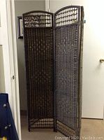 Front angled view showing the four-panel folding structure and woven rattan material with decorative geometric patterns.