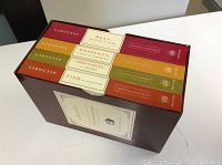 Wooden box holding four Larousse Gastronomique cookbooks showing book thickness and spine colors