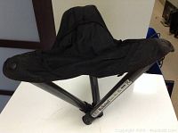 Foldable walk stool set up showing black fabric seat and metal legs with a stable three-legged construction