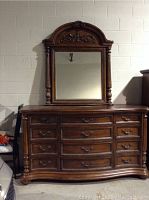 Front view of dresser with attached arched-top mirror against wall