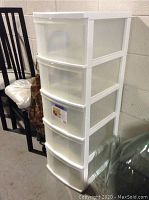 Photo showing a tall 5 drawer plastic storage unit with white frame and translucent drawers in a storage or garage setting.
