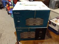 Two Baillie chandelier boxes stacked on a wooden table