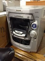 Front view of Panasonic stereo system SA-AK200 showing cassette decks, 5 CD changer, and control knobs.