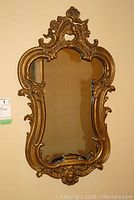 Full front view of the antique mirror showing ornate gilded frame and overall shape