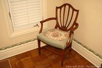 Full view of antique wood framed occasional chair showing curved shield backrest and armrests.