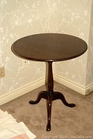 Full view of round wood pedestal table in room corner