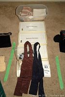 Lot arranged on carpet floor showing stacked boxed Banana Republic handkerchiefs, two bow ties placed on boxes, miscellaneous small pouches and a plastic bin with more fabric accessories.
