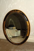 Full view of the oval mirror showing reflective surface and decorative frame details
