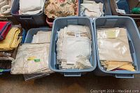 Bins and boxes with assorted vintage linens including lace tablecloths, placemats and napkins.
