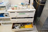 Top and side view of three white drawers, various ropes and cords on and inside drawers, with electrical items, light sockets, and other hardware around