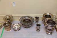Overview photo showing all silver plate items including ice buckets, vase, footed bowls, bowl and goblets arranged on floor against wall.