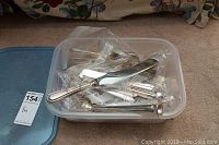 Plastic container holding assorted silver flatware including forks, spoons, knives and picks.