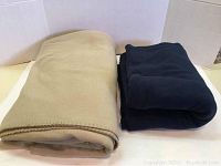 Two folded fleece blankets side by side, tan and blue colors