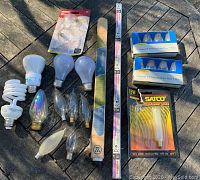 View of assorted lightbulbs including spiral compact fluorescent, standard incandescent, decorative flame-tip bulbs, string light bulbs, two packs of 4 C9 7 watt bulbs each, and a boxed Satco 15 watt decorative bulb.