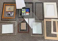 Collection of assorted frames, mats, glass, and small parts displayed on carpet floor.