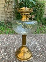 Full view of antique brass and glass lantern showing the overall shape and materials, outdoors background.