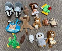 Overview of 15 plush stuffed animal toys including badgers, dog, frog, crab, owls, lion, chipmunk, squirrel, leopard and a blue bag