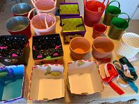 Photo of assorted containers, planters, and gift boxes including metal, fabric, ceramic, and plastic pieces in various colors and styles.