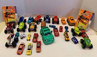 Photo showing a variety of toy vehicles neatly arranged, including two Matchbox packaging cards in the background.