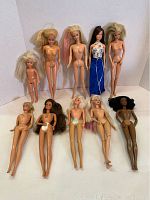 Lot of 10 Barbie dolls displayed standing and sitting. Various hair colors and styles visible, most undressed except one doll wearing a blue and white dress.