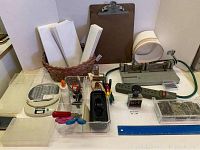 Overview of entire assortment including envelopes, clipboard, hole punch, scissors, tape dispenser, and scale