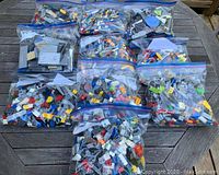 Ten resealable plastic bags full of various LEGO bricks in multiple colors and shapes.
