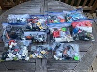 Overview of all 11 ziplock bags containing various LEGO parts showing wide variety of pieces including wheels, bricks, and specialized parts.