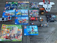 Photo showing all 7 LEGO manuals alongside their corresponding built vehicles arranged on a wooden surface.