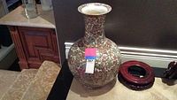 Full side profile view of the large Asian porcelain vase or umbrella stand with its wooden stand beneath. Shows colorful ornate design and wide opening at the top.