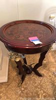 Full view of round inlaid walnut table with decorative edge and brass eagle leg accents