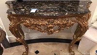 Front view of console table showing marble top and carved base
