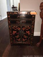 Front view of black Asian-inspired nightstand showing drawer, doors, and decorative butterfly and floral motifs.