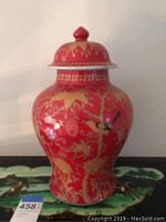 Front view of the Chinese porcelain ginger jar showing detailed gold floral patterns and painted birds on red background with Chinese script.