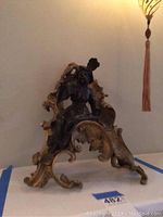 Front angled view showing ornate scroll design and seated figure